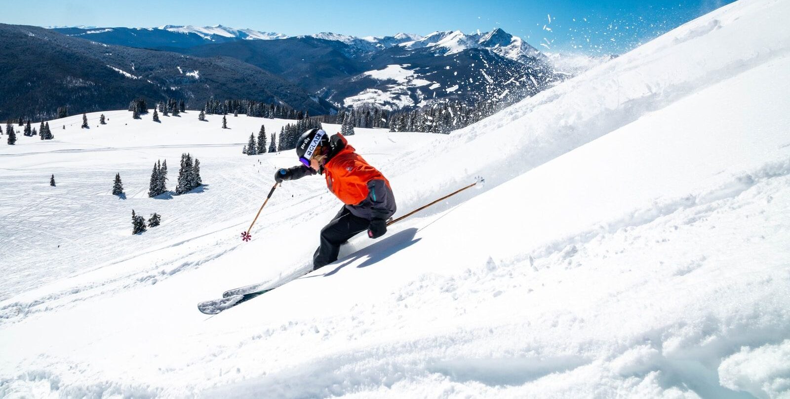 person in orange jacket and black pants riding ski blades on snow covered mountain during daytime